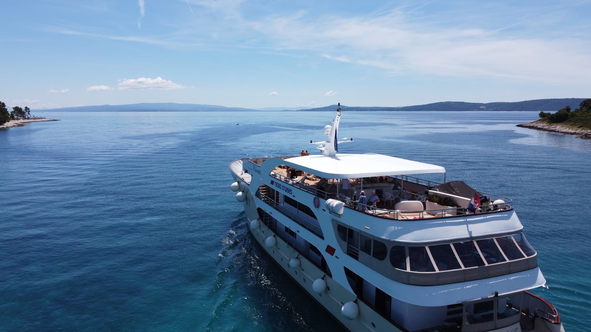 Cruise ship sailing on blue coastal waters between islands