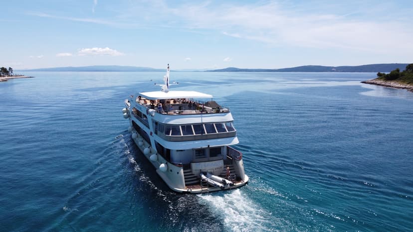 Large cruise yacht sailing on calm blue sea with distant coastline