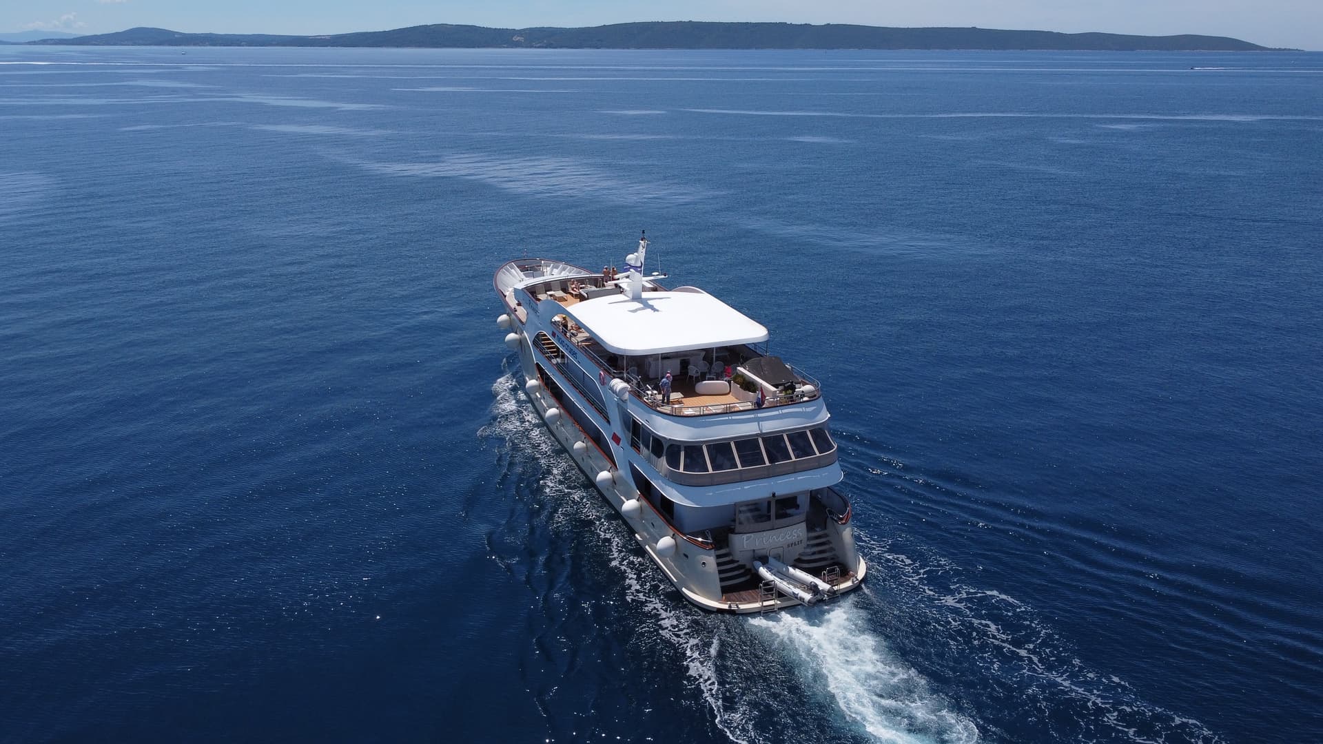 Cruise ship sailing on open sea water with distant coastline