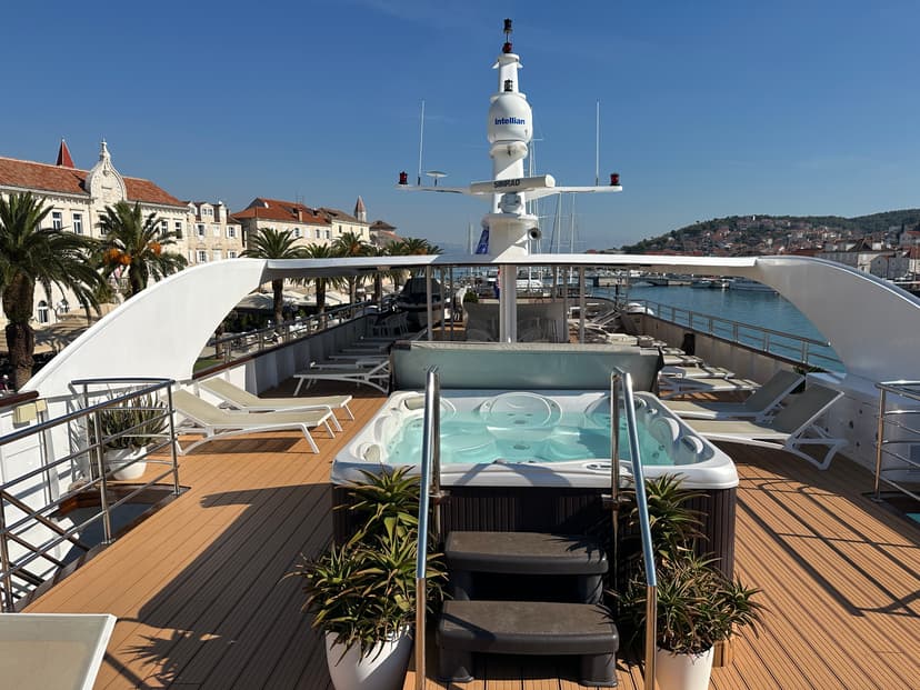 Yacht sun deck with hot tub, lounge chairs, and coastal town backdrop