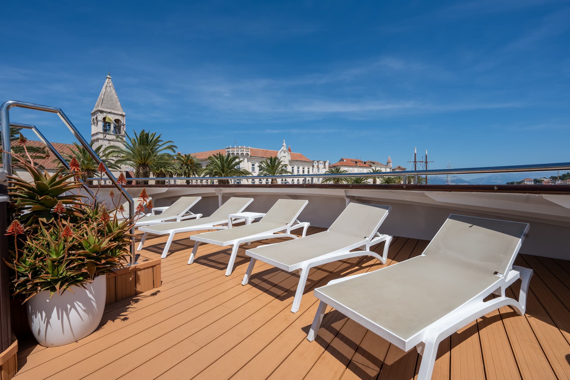 Sun loungers on wooden deck of cruise ship with coastal town view