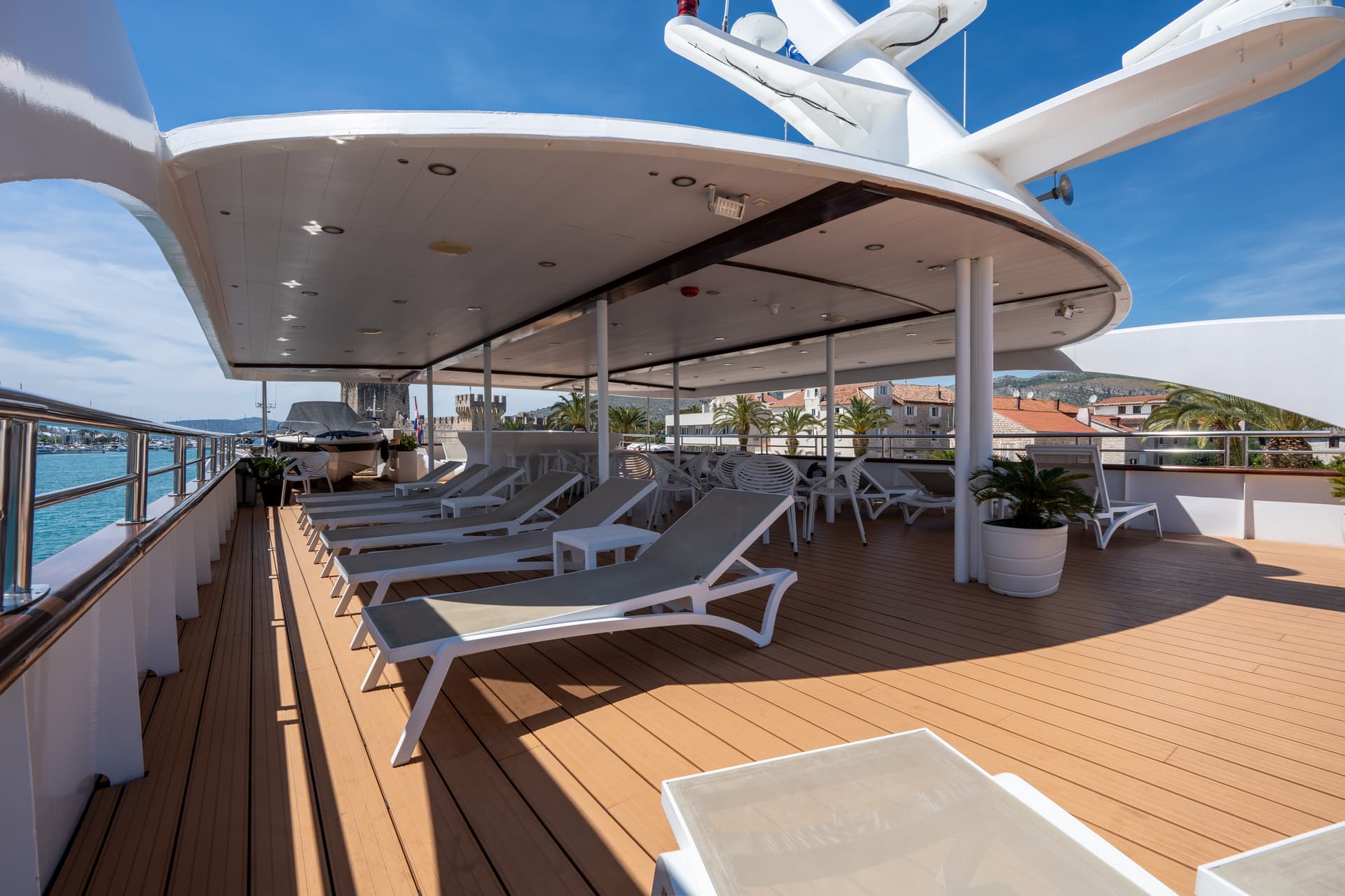 Sun loungers on the shaded deck of a luxury yacht with coastal views