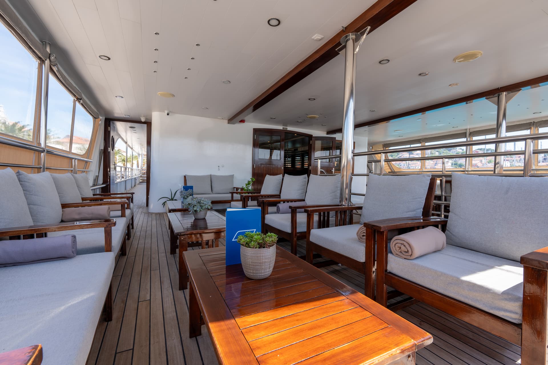 Lounge area with wooden furniture and gray cushions on a boat deck