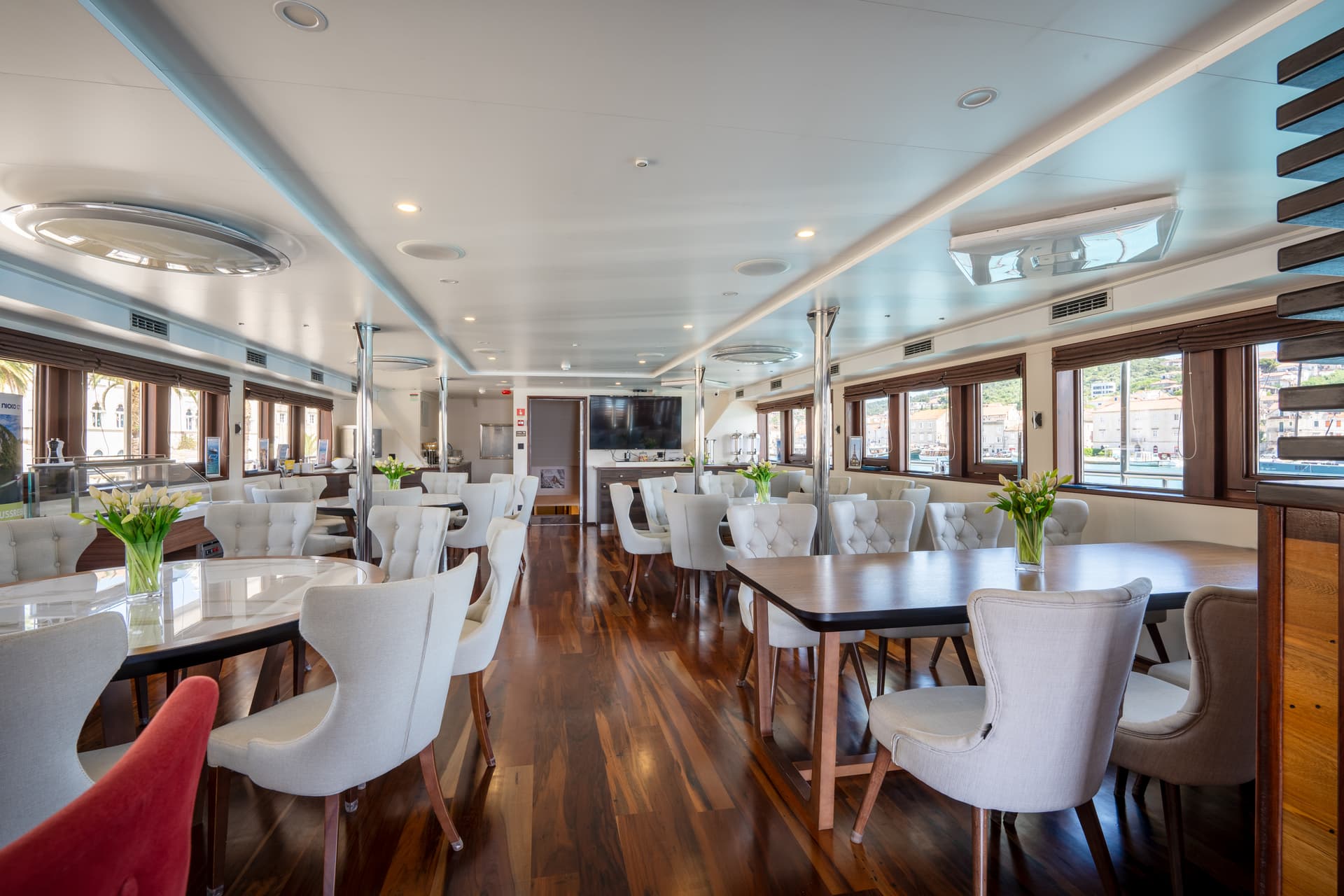 Modern restaurant and lounge interior with upholstered chairs and wooden floors on a cruise ship