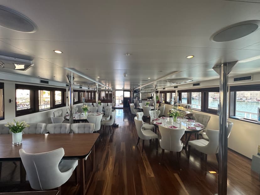 Restaurant and lobby bar interior with set dining tables and white chairs on a yacht.