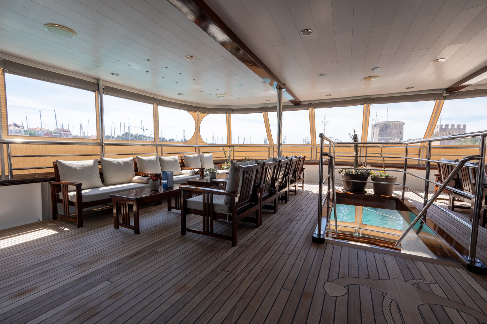 Lounge bar on wooden deck of cruise ship with seating and harbor views