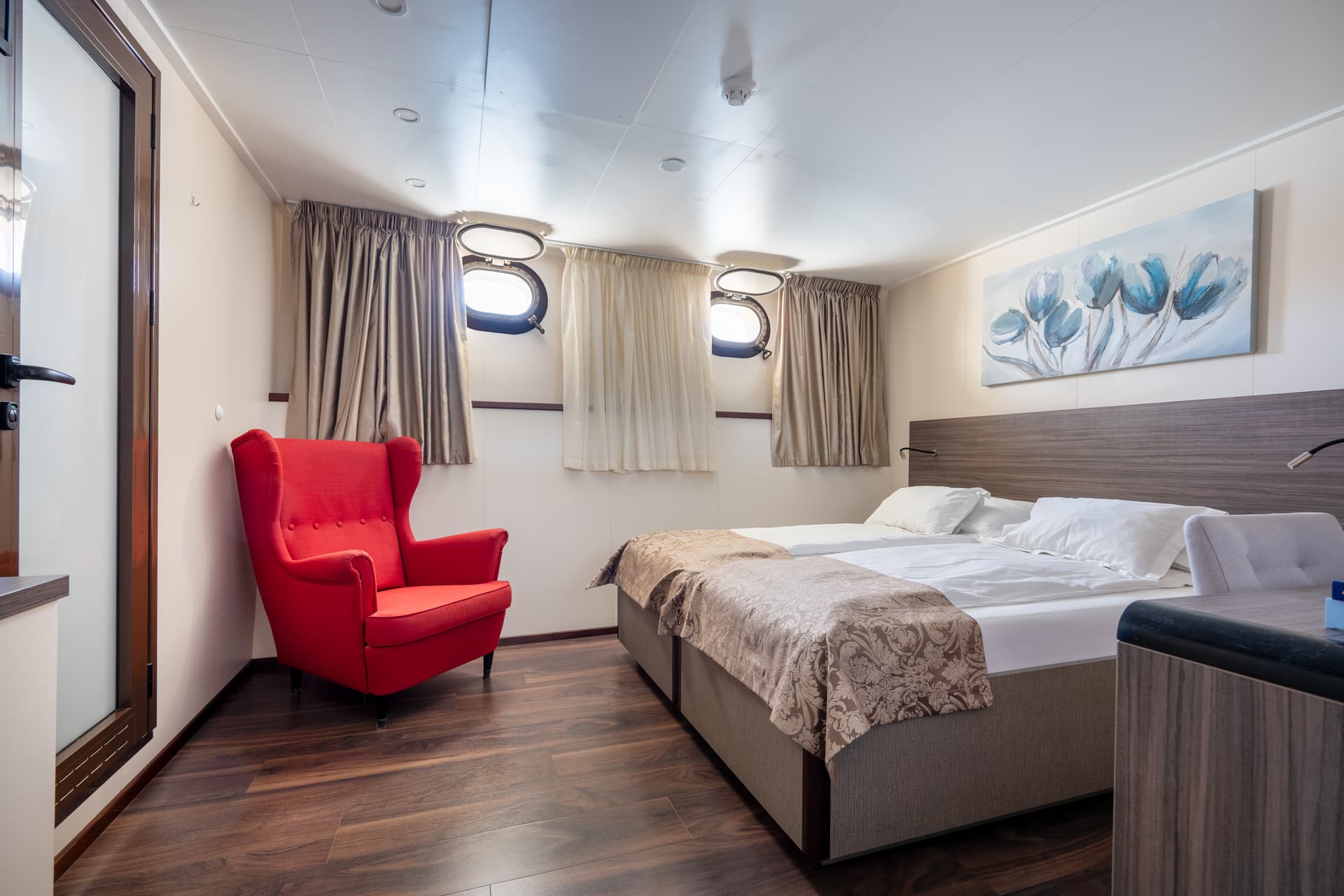 Cruise ship standard cabin with twin beds and bright red armchair