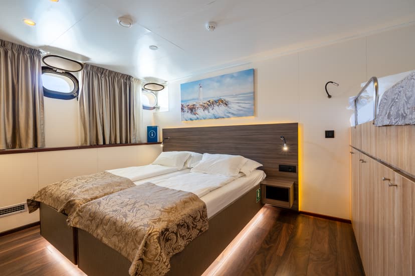 Standard cruise ship cabin interior with twin beds and portholes
