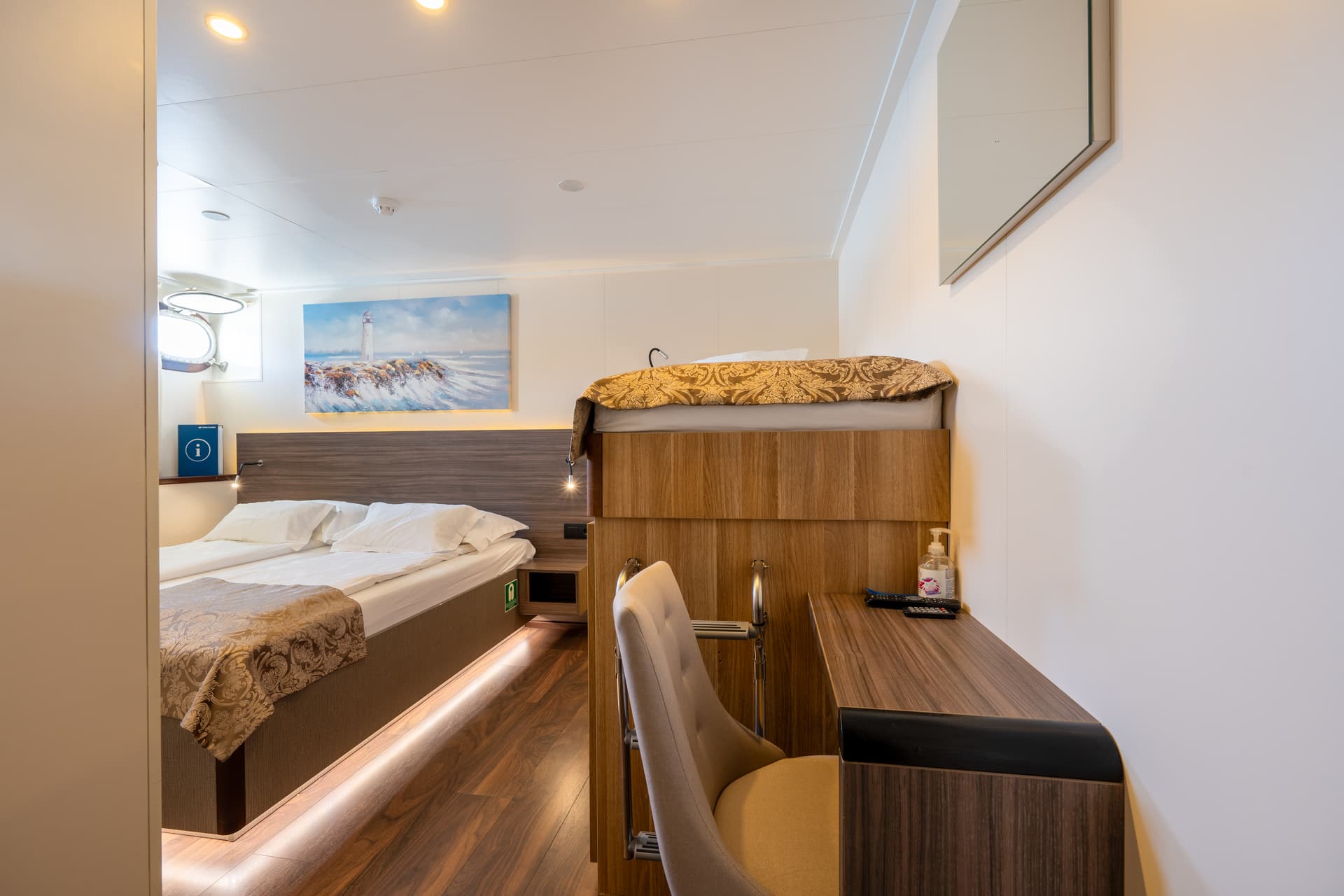 Standard cabin interior on a cruise ship with bed, desk, and chair