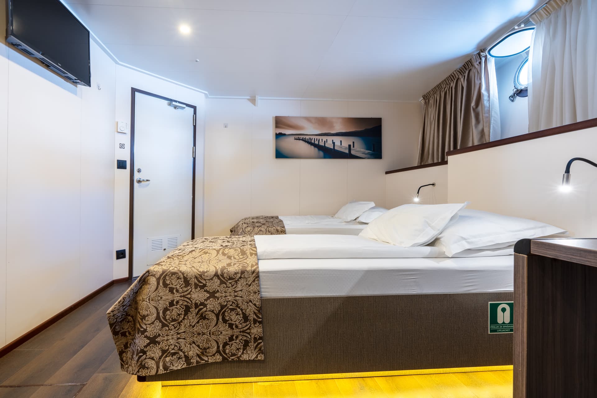 Standard twin cabin on boat with two beds and porthole window