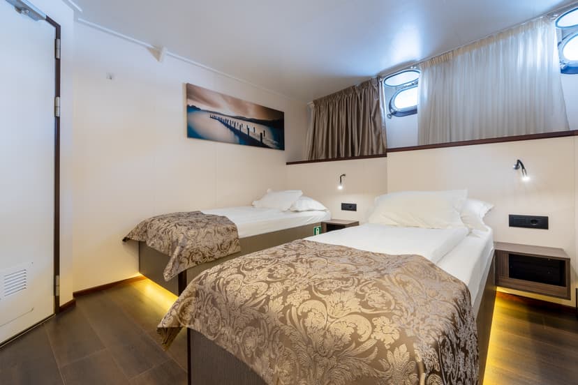 Standard cabin on cruise ship with twin beds and portholes