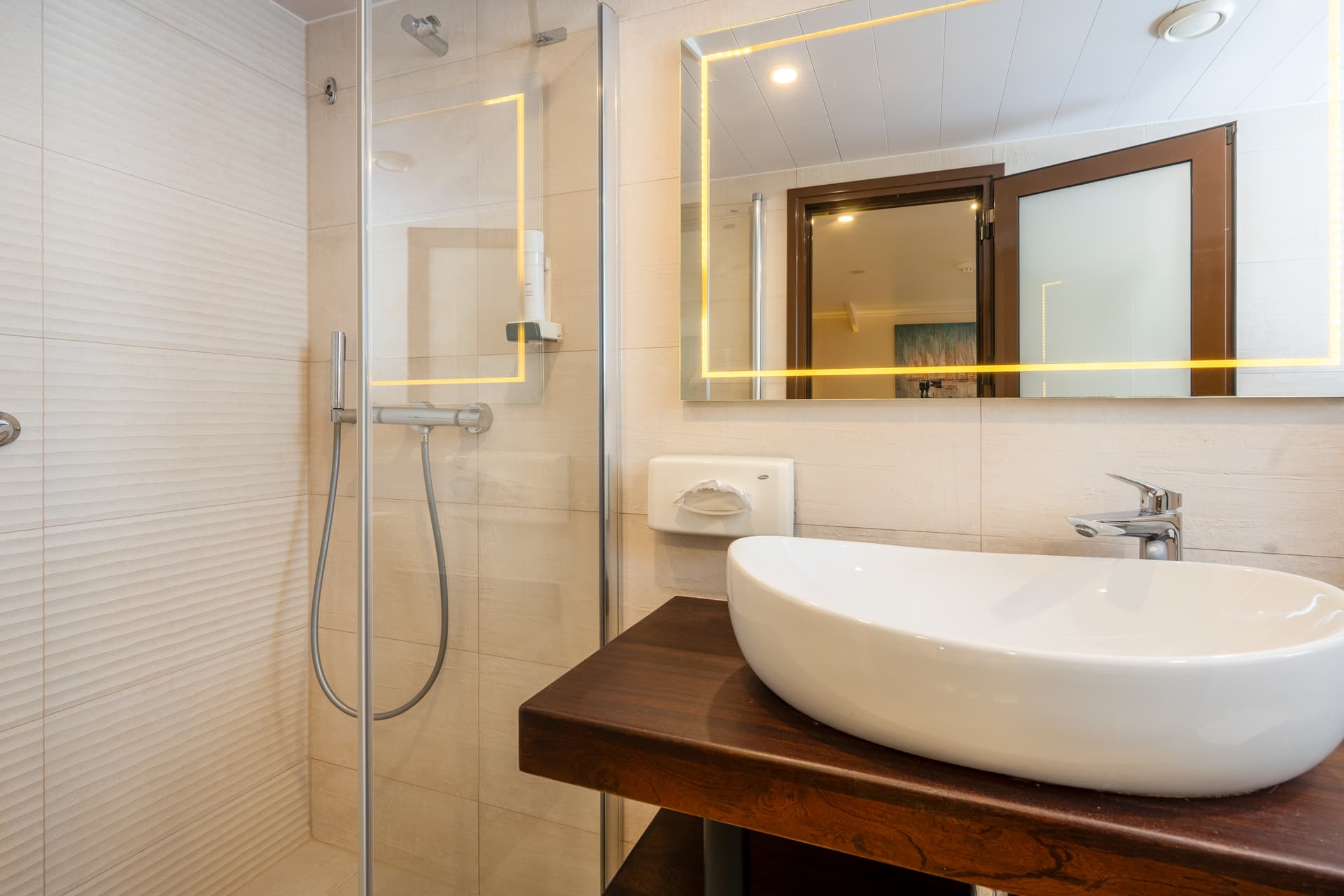 Modern bathroom with vessel sink on wooden vanity and glass shower stall