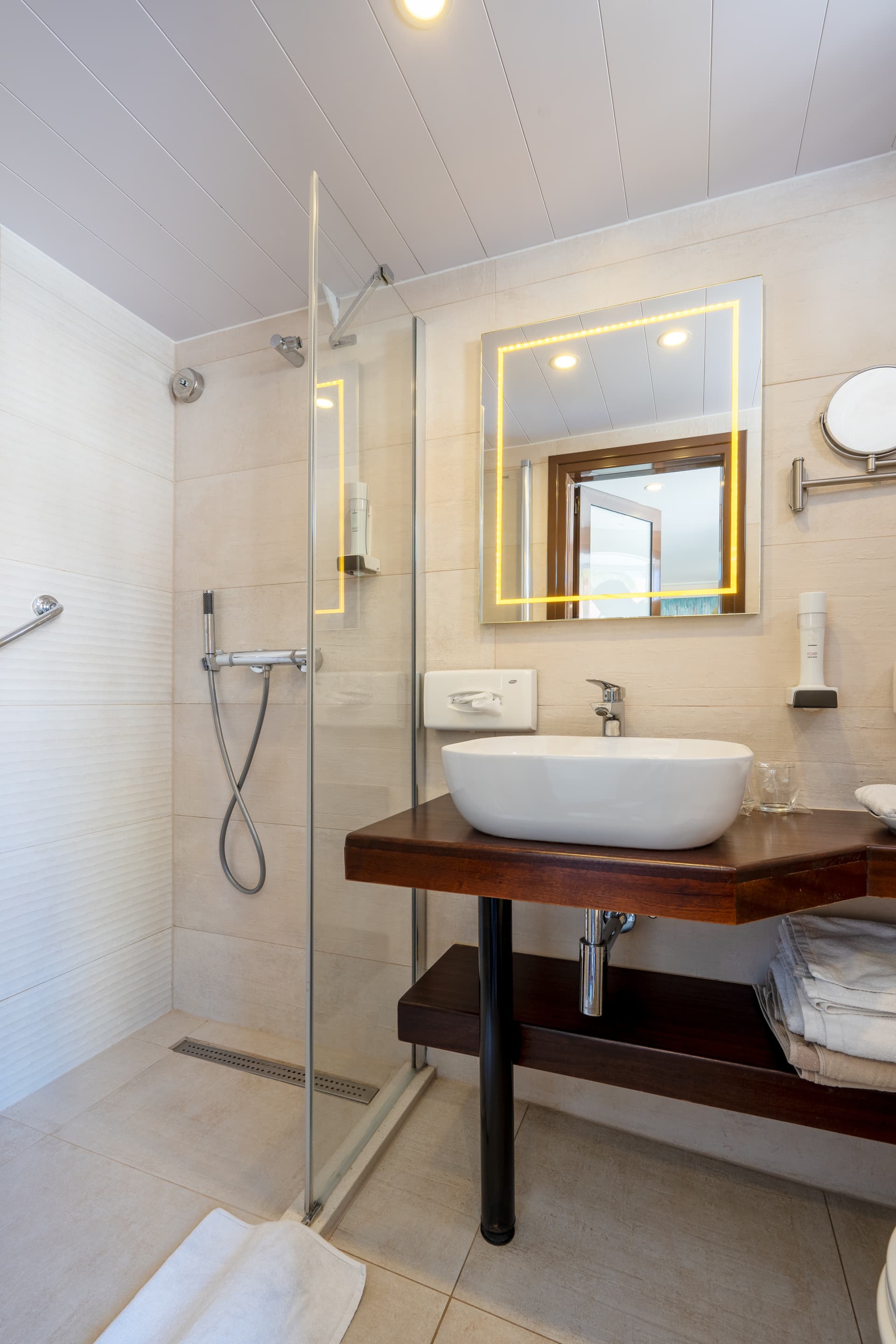Modern hotel bathroom with glass shower enclosure and vessel sink vanity