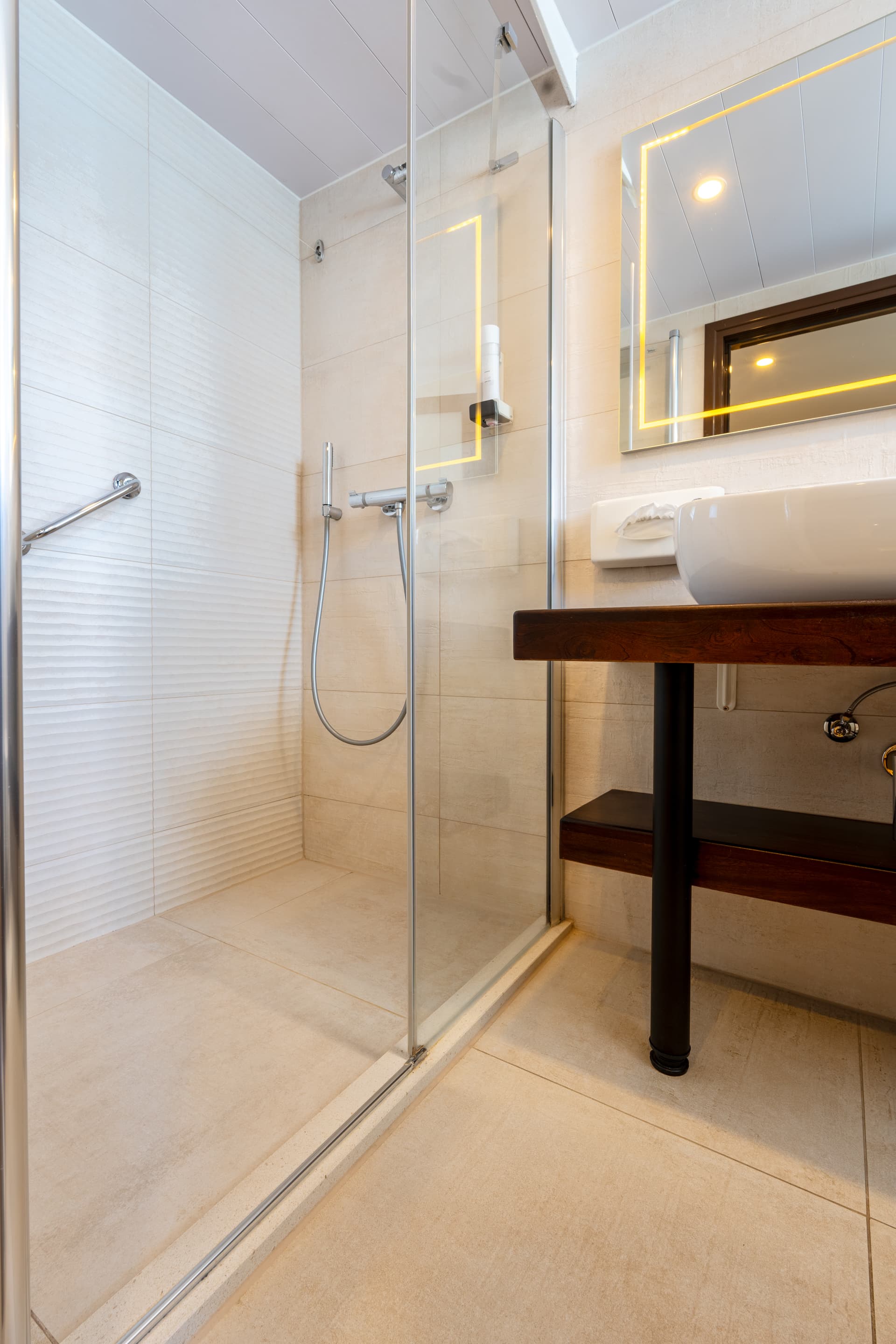 Modern bathroom with glass shower enclosure and wooden vanity sink