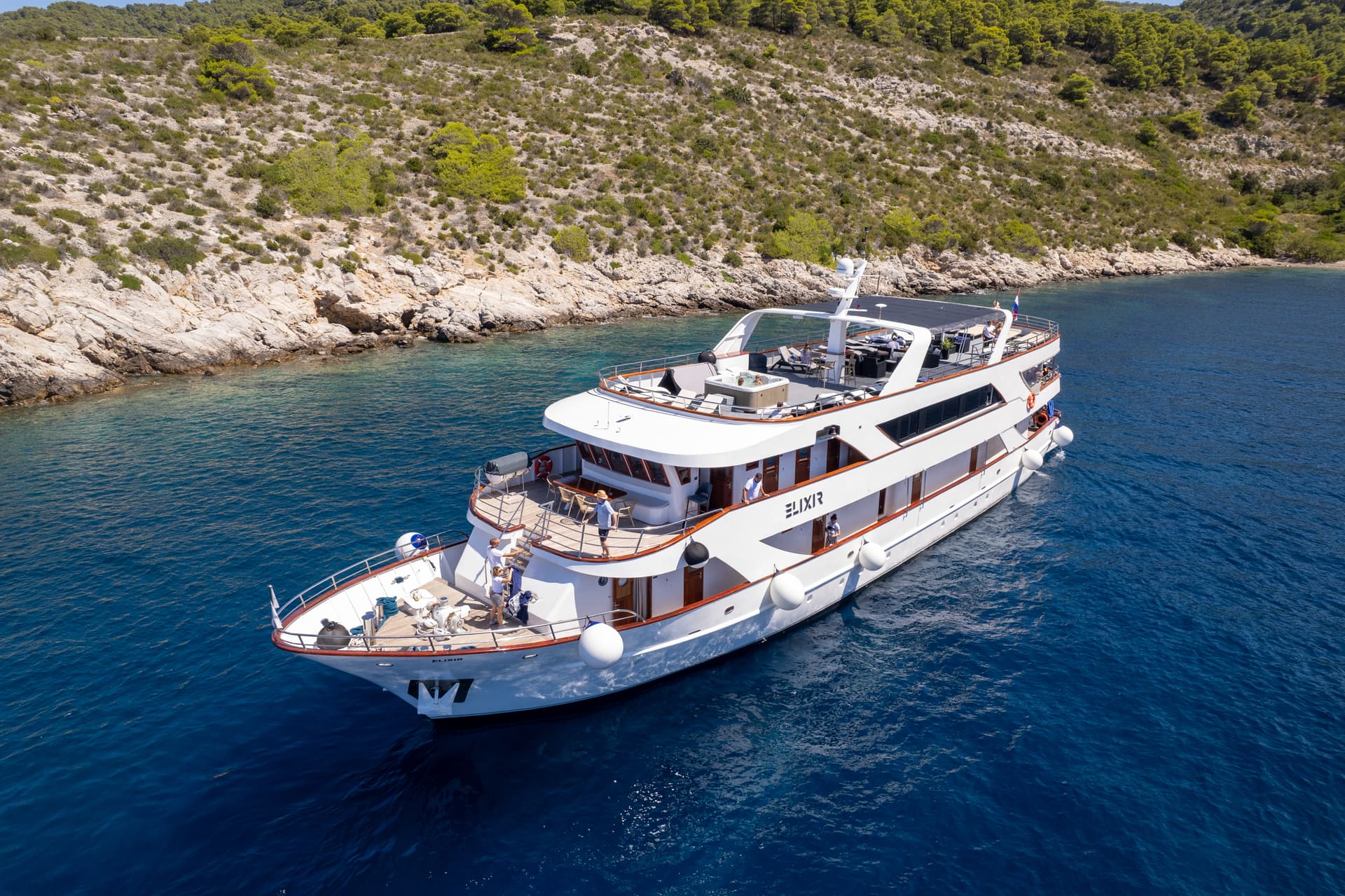 White luxury yacht cruising on blue coastal waters near rocky hills