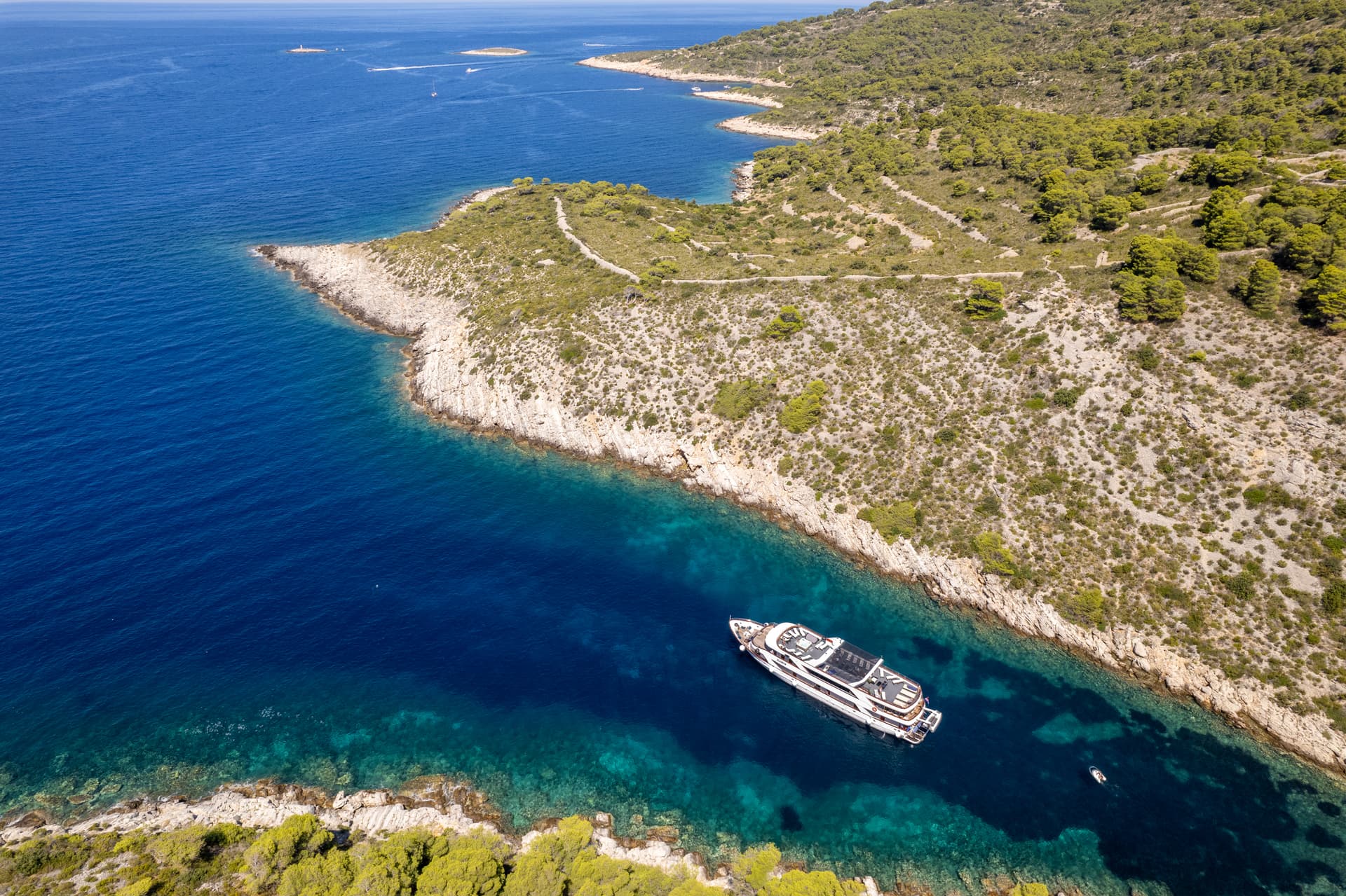 Yacht anchored in a secluded cove with rocky cliffs and blue coastal waters