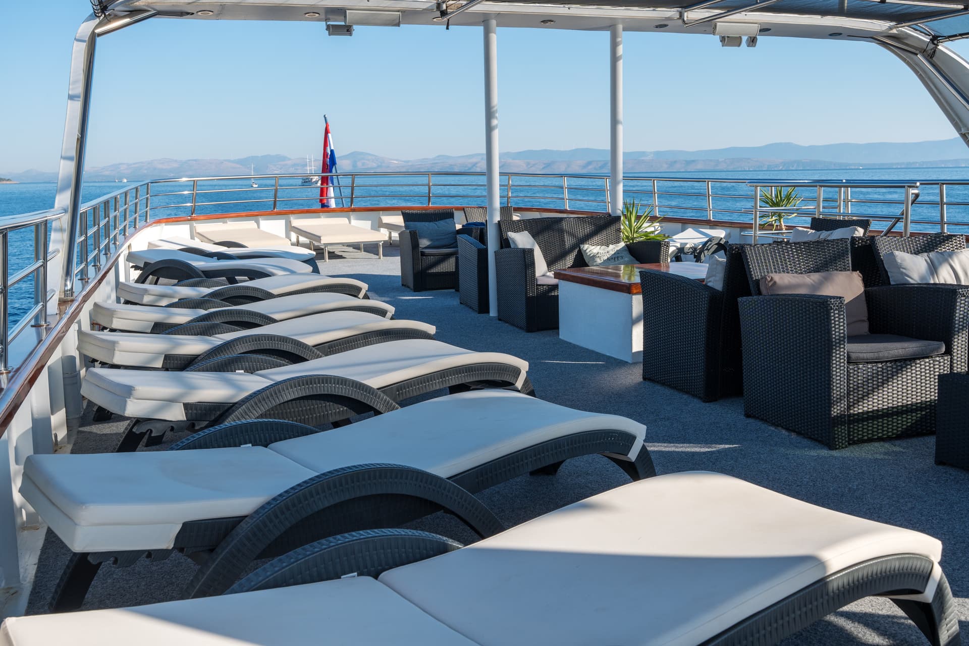 Lounge chairs and seating area on yacht deck overlooking sea and distant coast