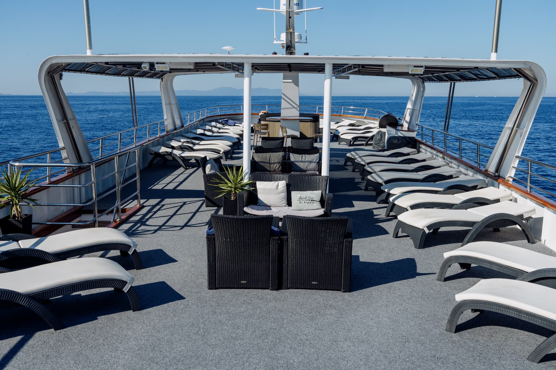 Lounge chairs and seating area on the deck of a boat with ocean view