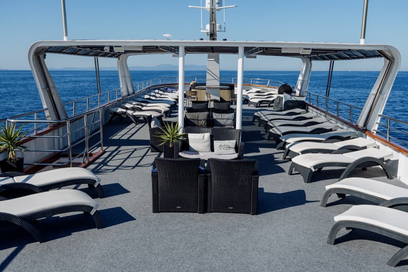 Lounge chairs and seating area on the deck of a boat with ocean view