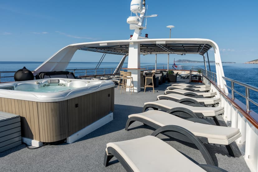 Luxury yacht deck with hot tub and lounge chairs on calm blue sea