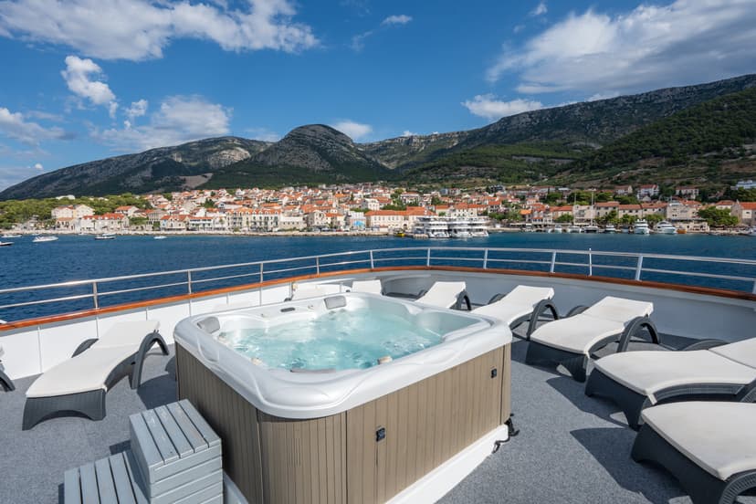 Jacuzzi hot tub and sun loungers on a yacht deck overlooking a coastal town and mountains