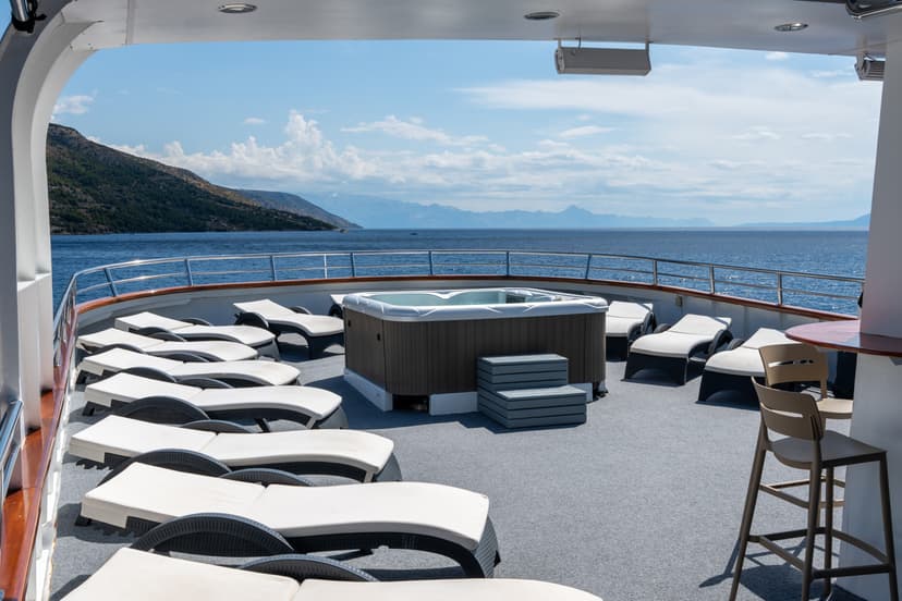 Yacht deck with hot tub and lounge chairs overlooking coastal mountains