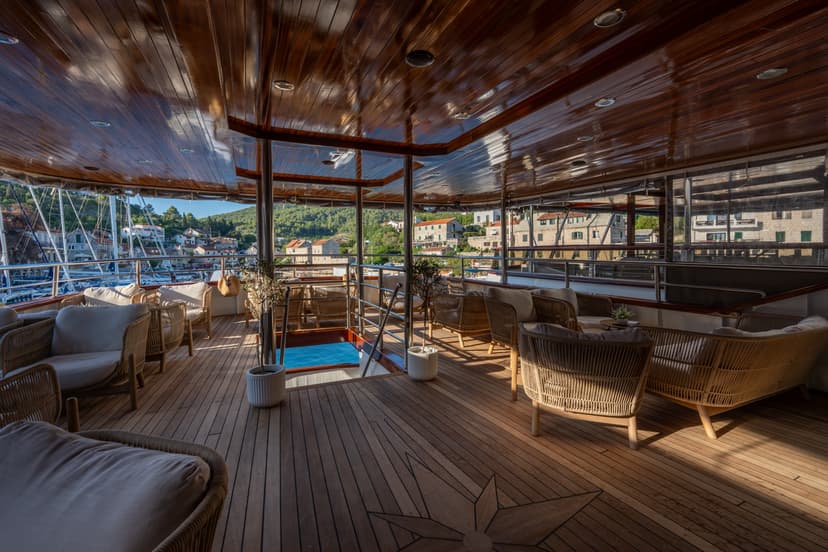 Luxury yacht deck lounge with wooden flooring and comfortable seating facing a harbor view