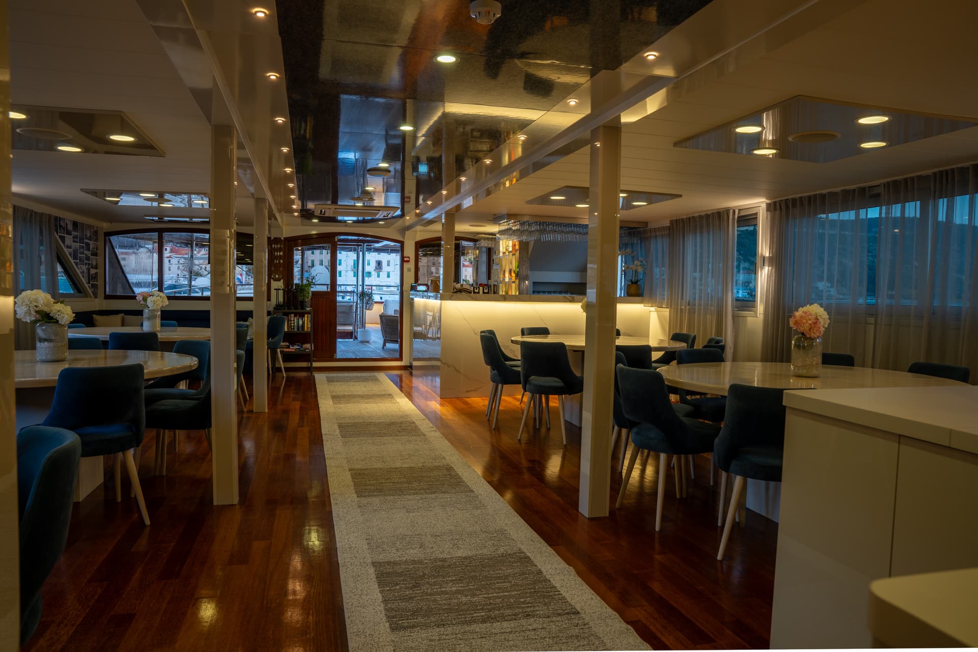 Luxury yacht interior dining lounge with blue chairs and wooden flooring