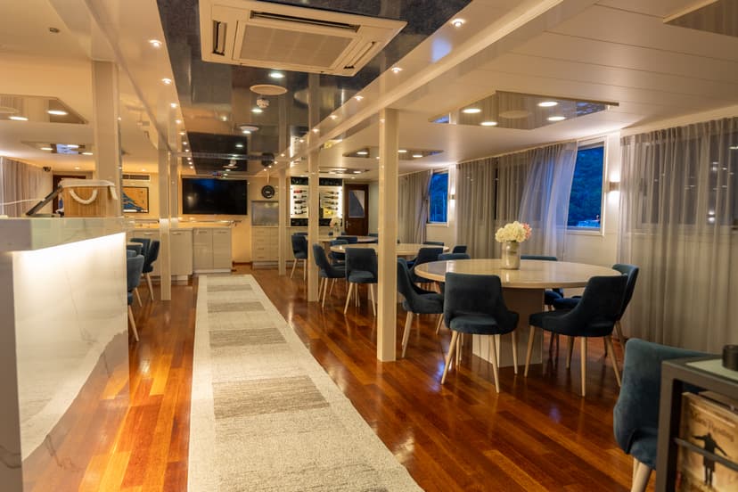 Modern cruise ship dining room with round tables and blue velvet chairs on wooden floors