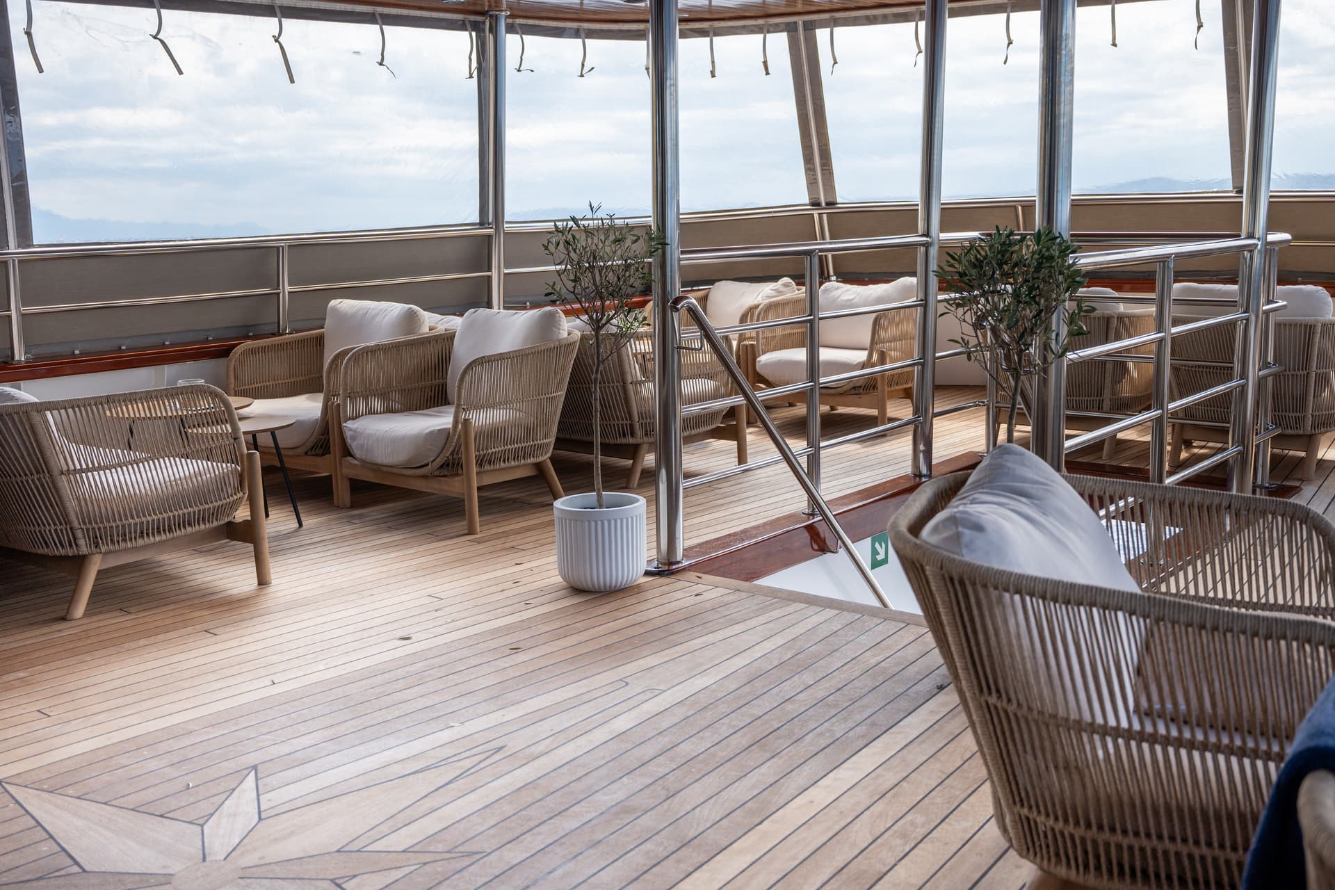 Wicker armchairs and sofas with white cushions on a wooden yacht deck