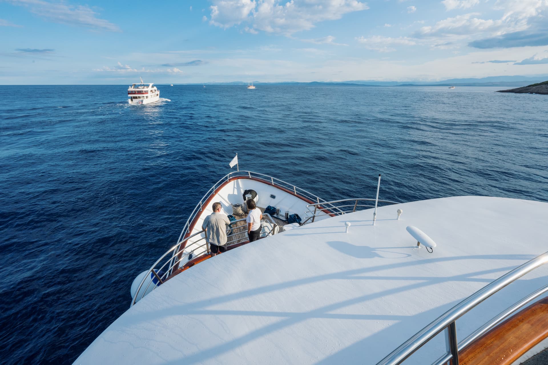 View from the bow of a yacht on blue sea with other boats in the distance