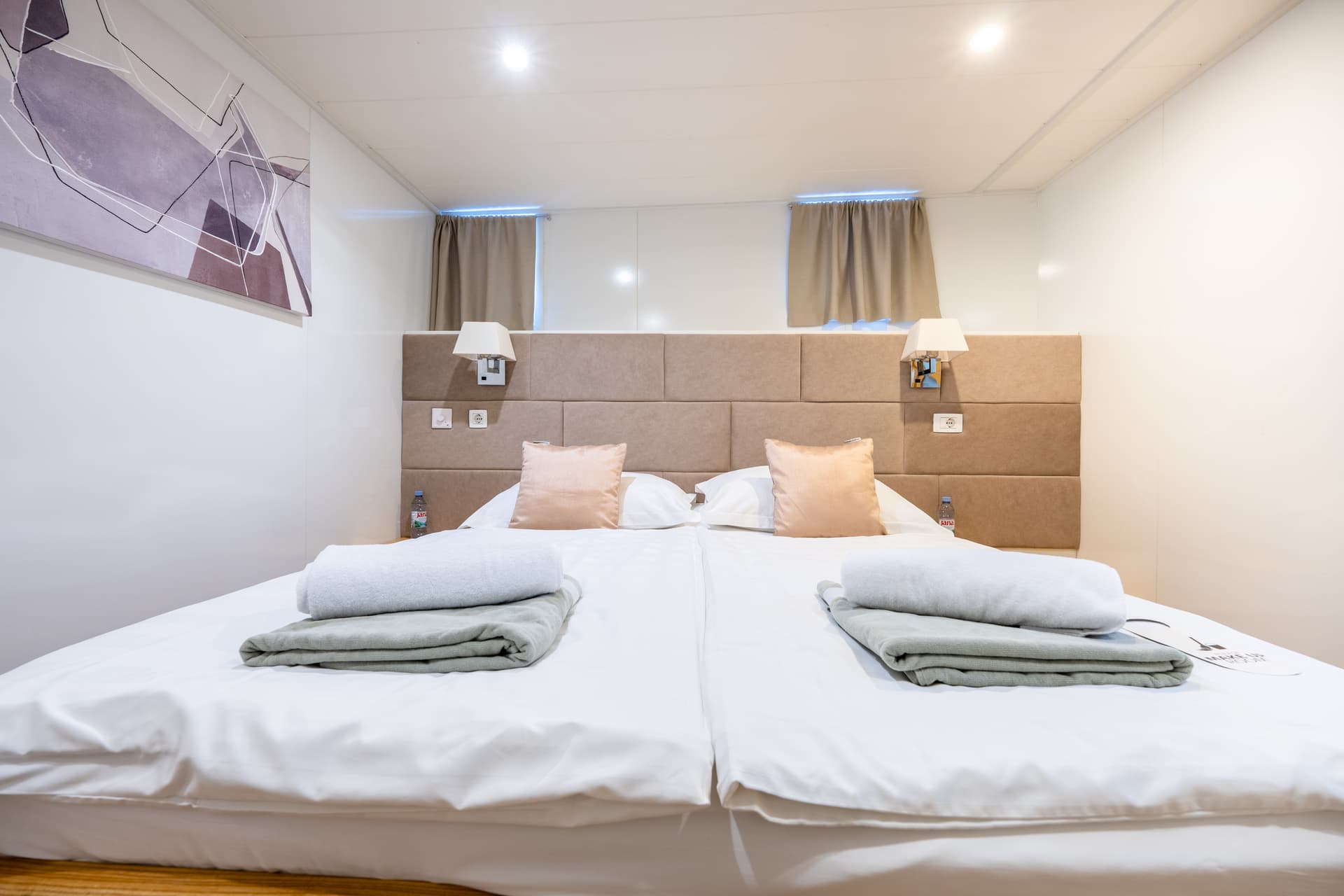 Modern hotel bedroom interior with neatly made twin beds and folded towels