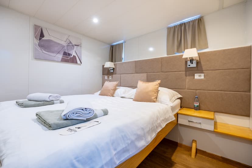 Hotel bedroom with large double bed, folded towels, and wall art