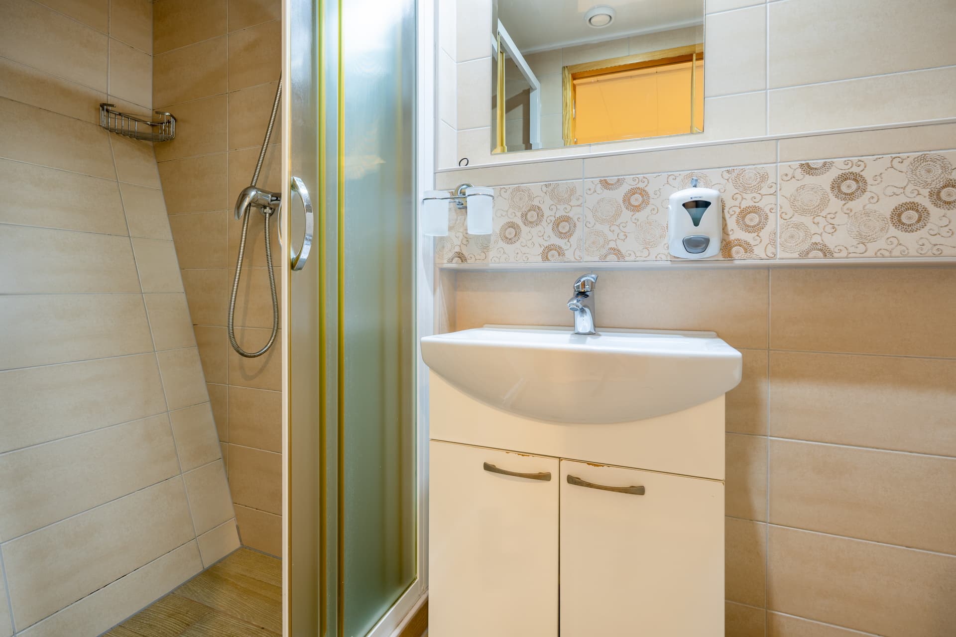 Bathroom with white sink vanity, shower stall, and patterned tile walls