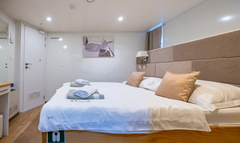 Hotel room with double bed, white linens, and folded towels
