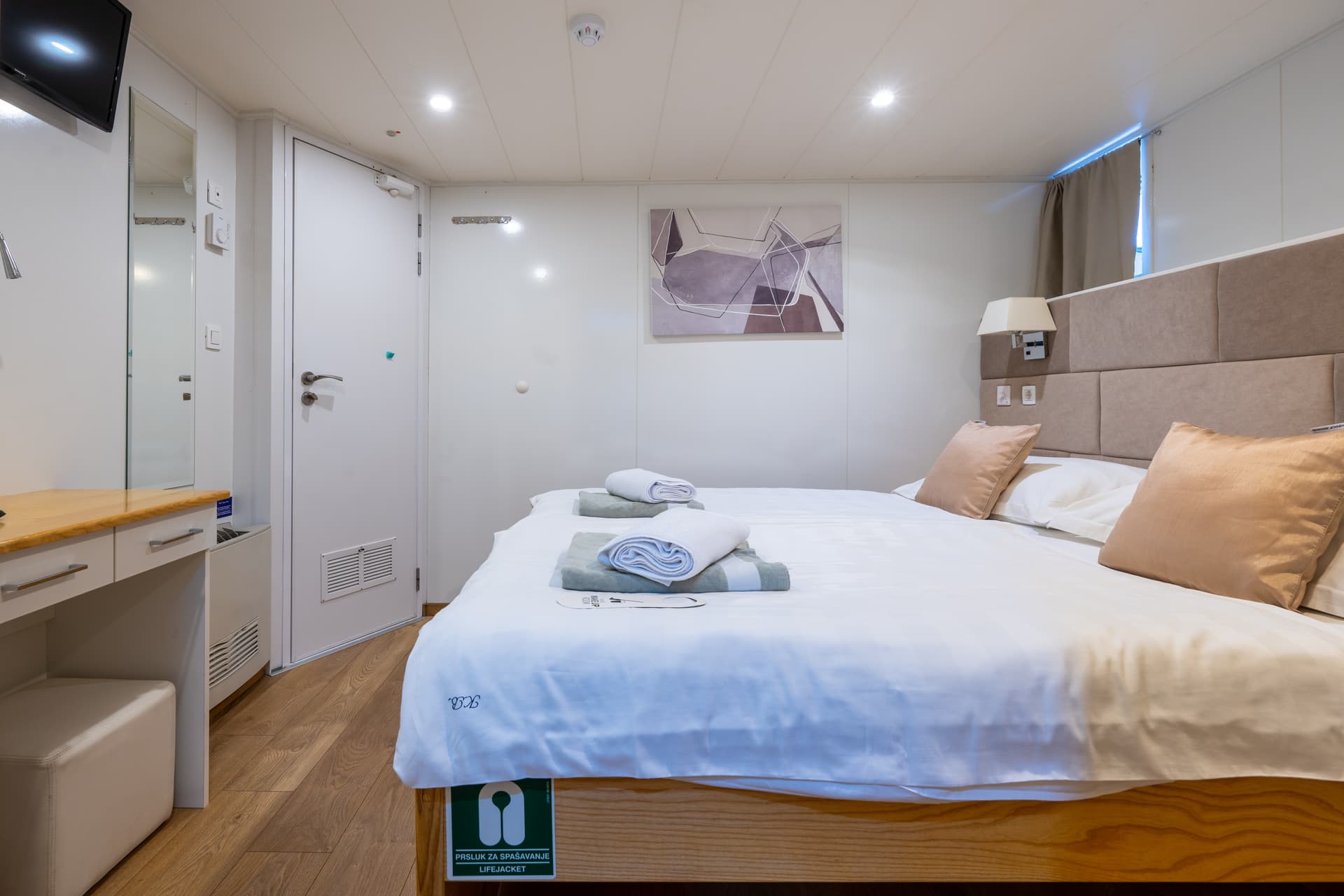 Cruise ship cabin interior with double bed and wooden floor