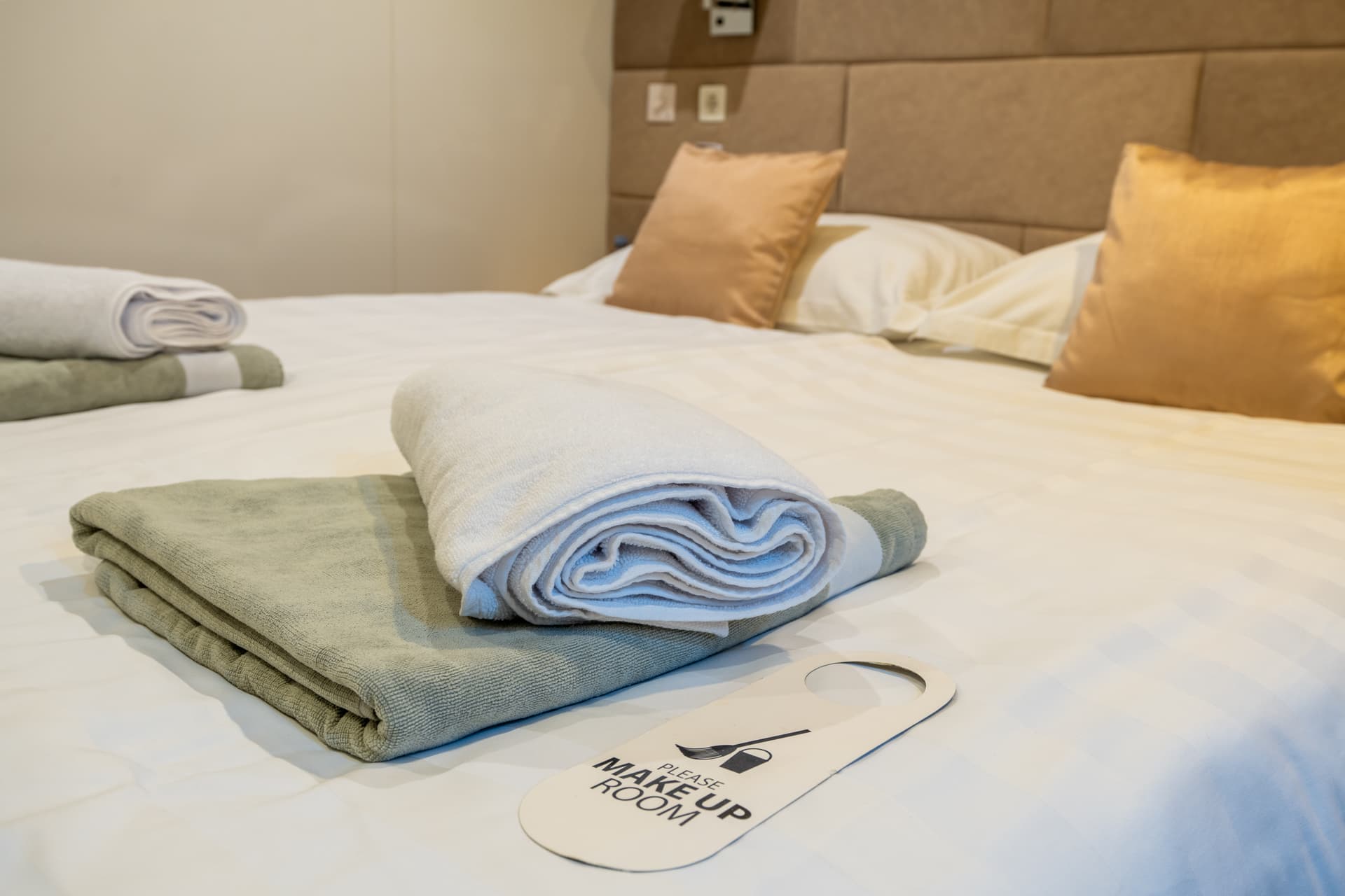 Hotel bed with folded towels and make up room sign