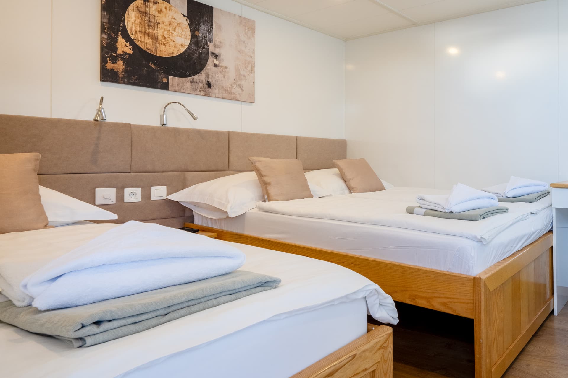 Hotel room with two twin wooden beds, white linens, and abstract wall art