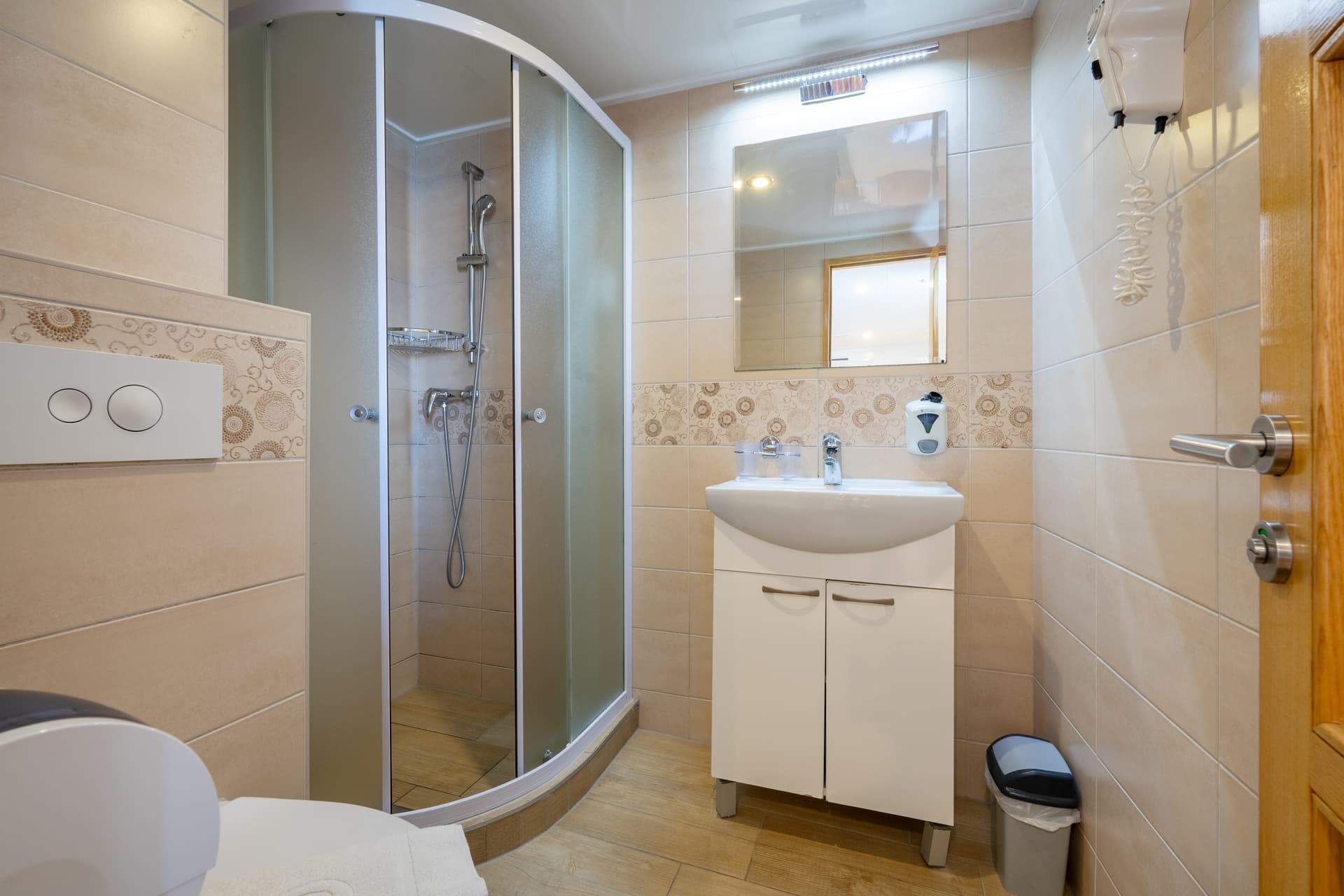 Modern bathroom with corner shower, white sink vanity, and tiled walls