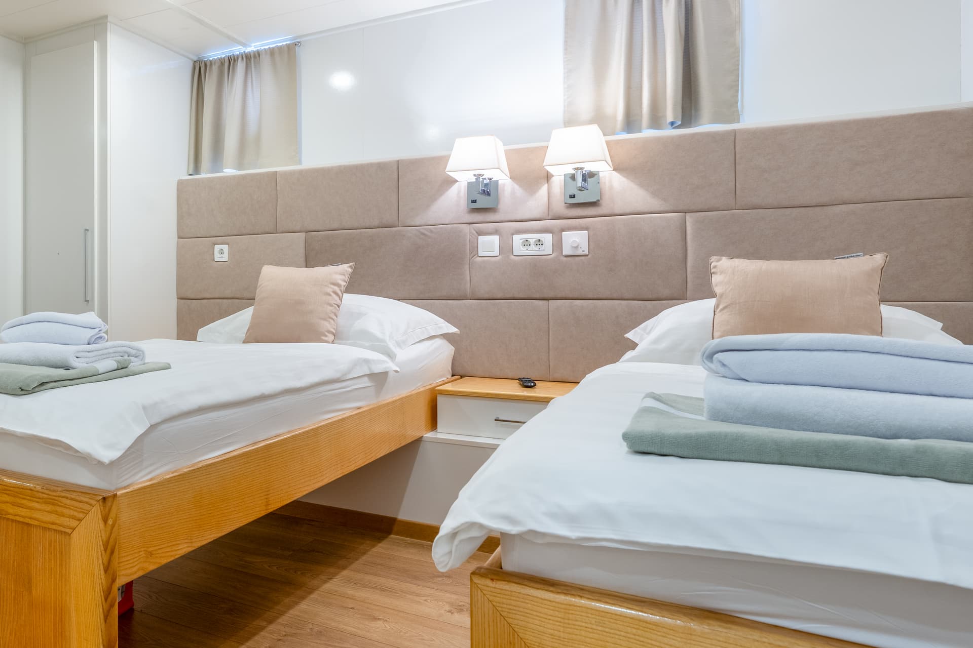 Twin beds with white linens and folded towels in hotel room