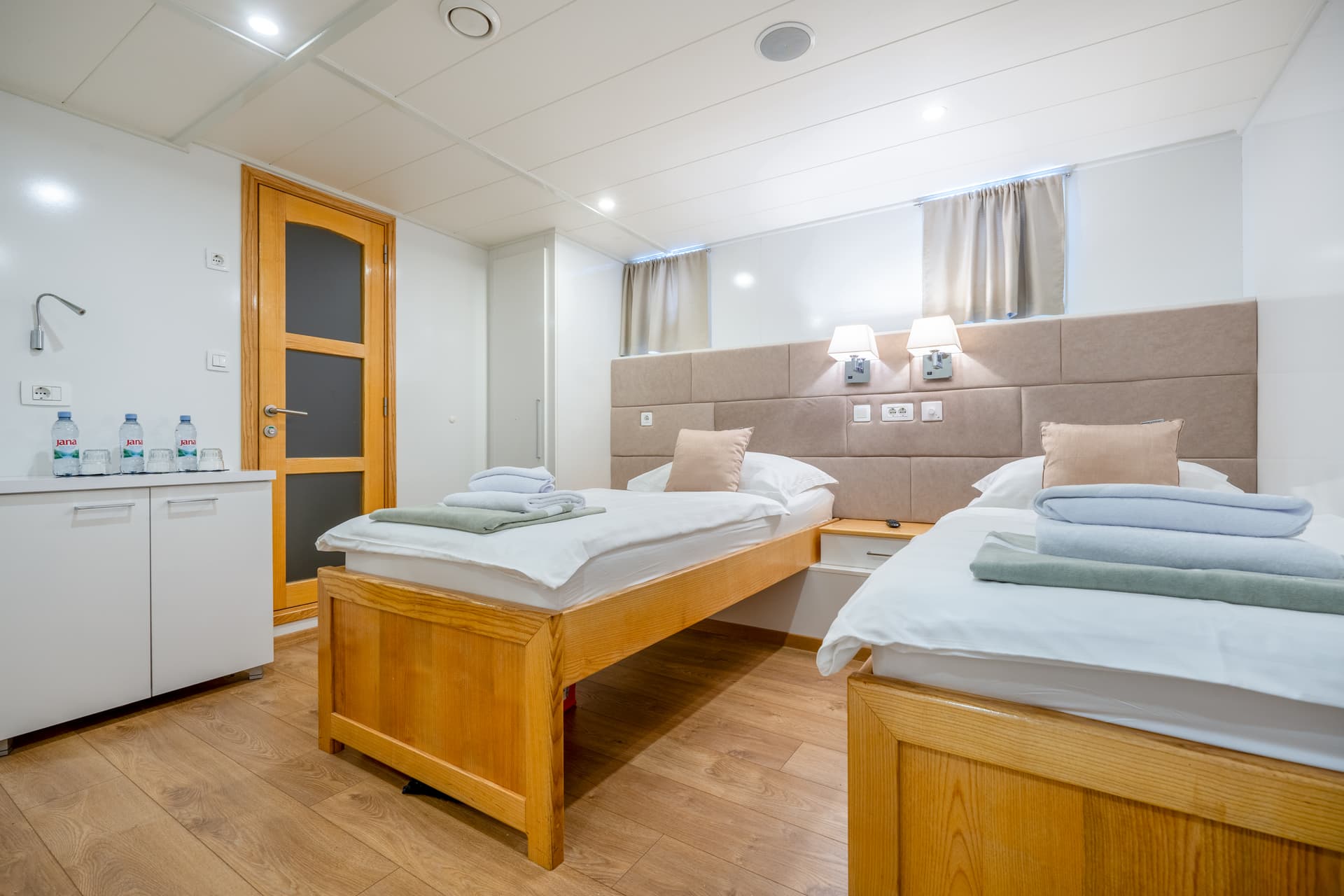 Twin beds in a modern cabin with wooden frames and neatly folded towels