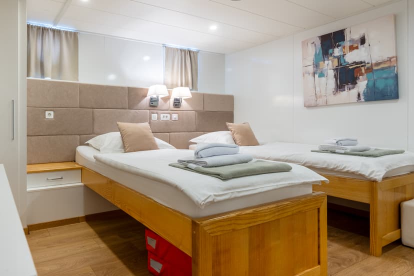 Modern bedroom with twin wooden beds, white linens, and abstract wall art