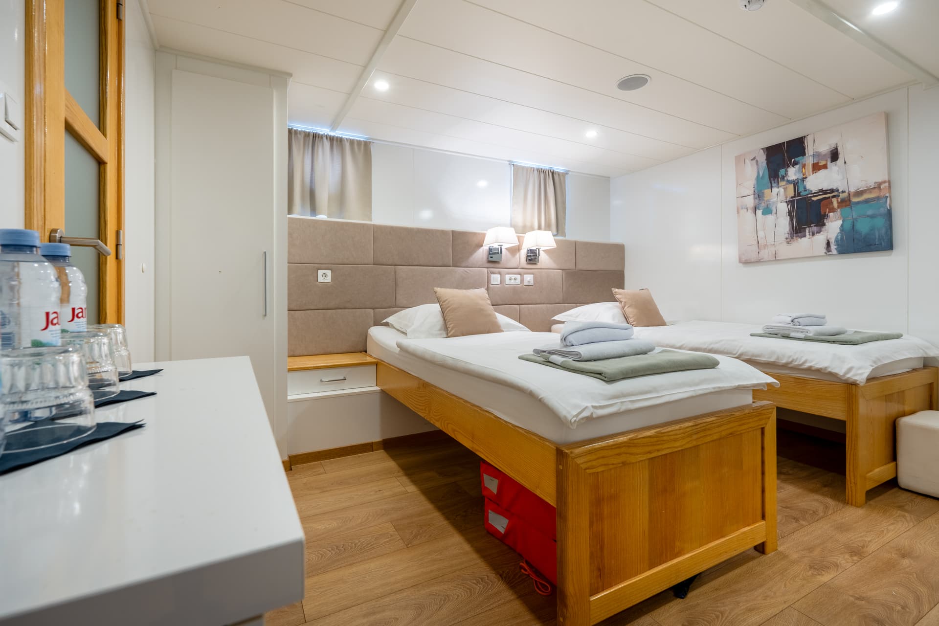 Twin cabin bedroom interior with wooden beds and abstract art on white walls
