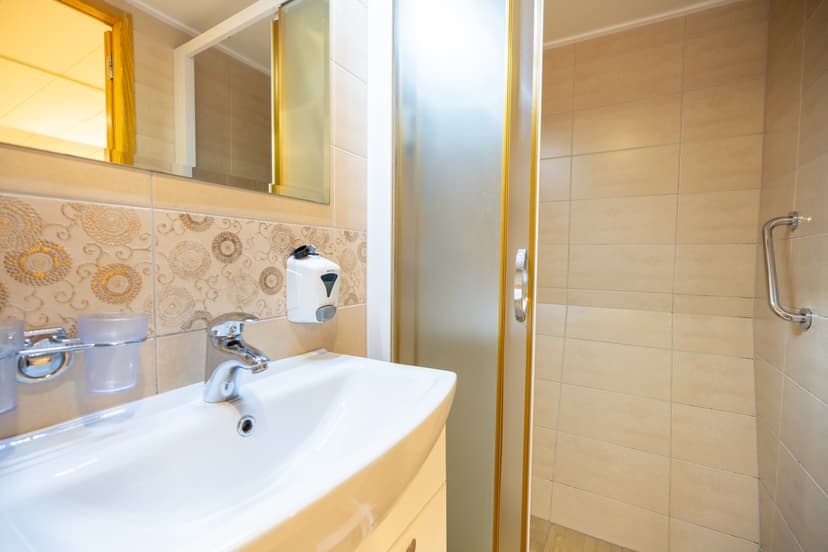 Hotel bathroom sink and shower stall with beige tile walls
