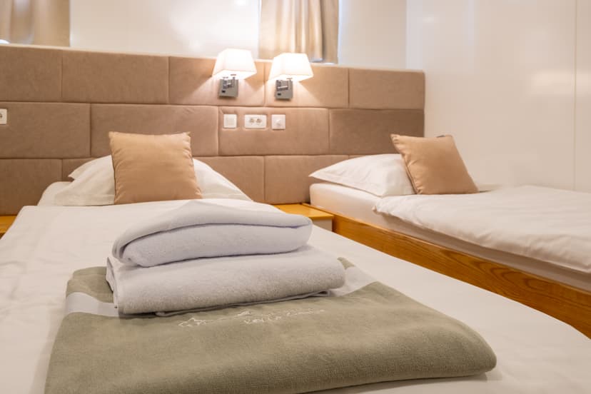 Hotel room with two twin beds and folded white towels on white linens