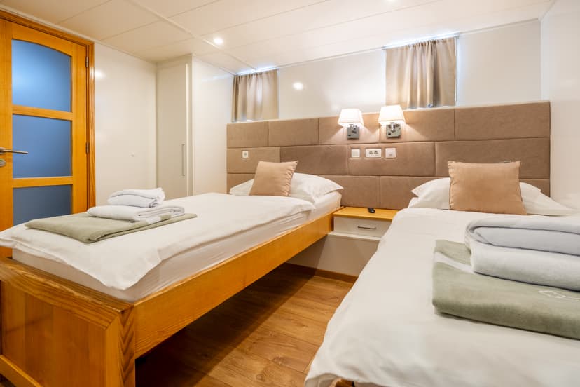 Twin cabin bedroom with two single beds, folded towels, and wooden accents