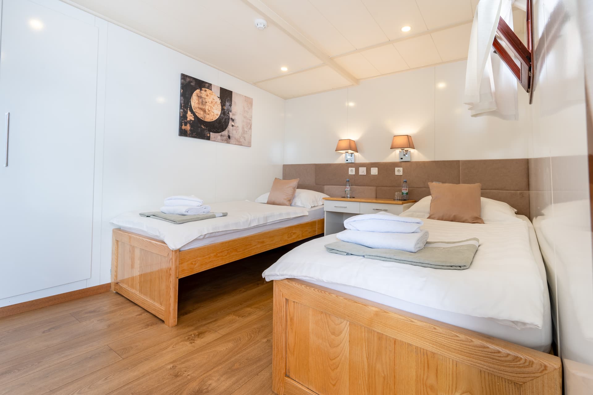 Twin hotel room with wooden beds and abstract wall art