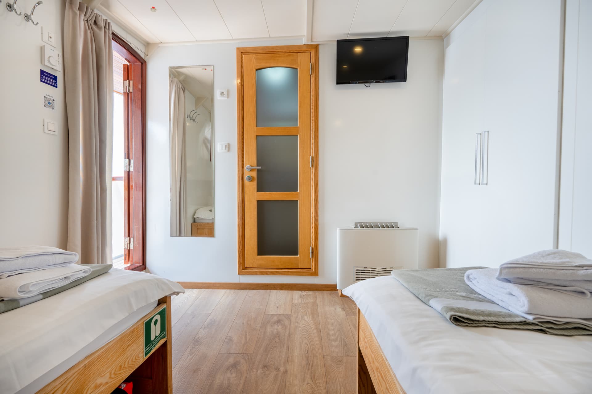 Twin cabin interior on a cruise ship with two beds and a wooden door