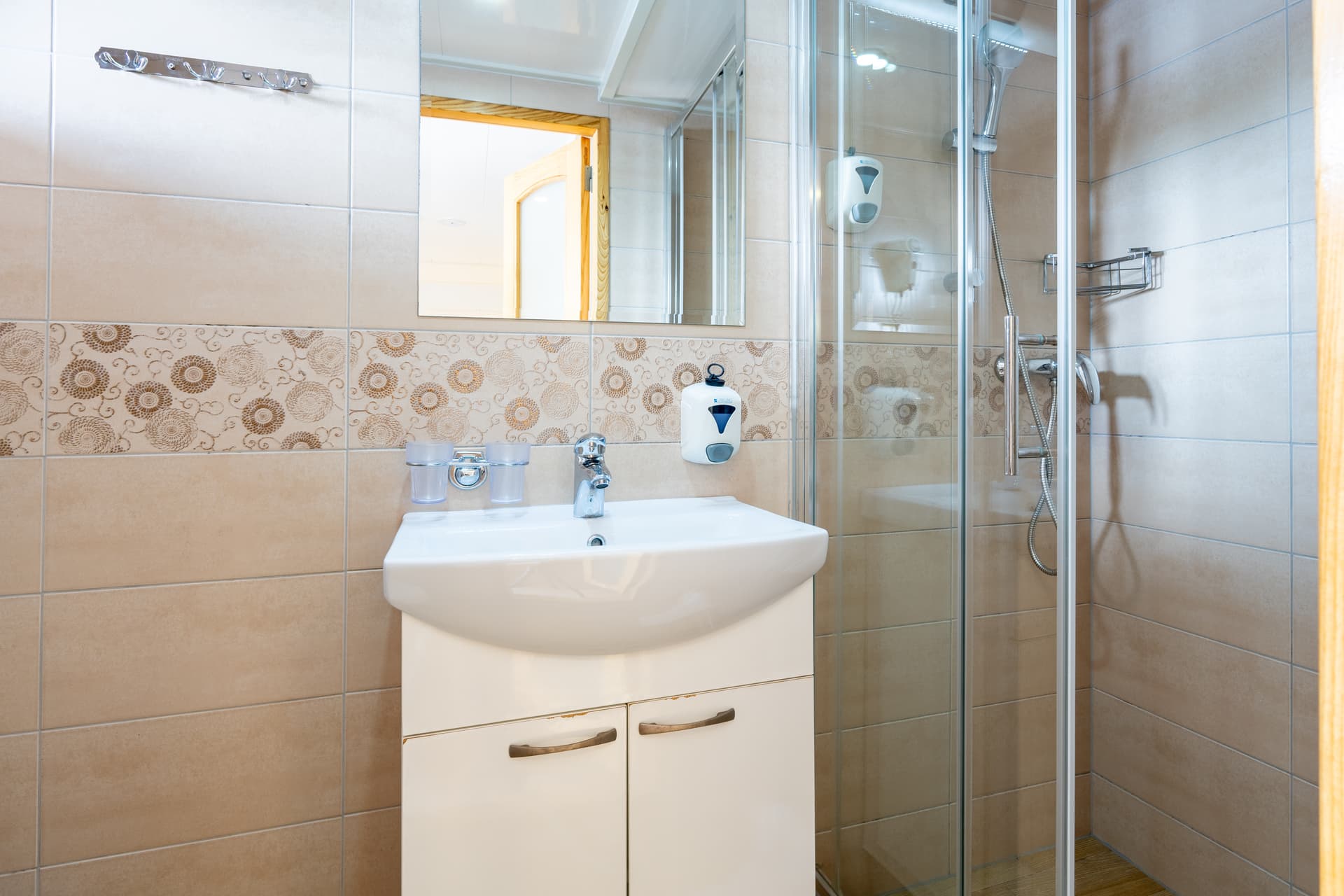 Modern bathroom interior with white sink, vanity cabinet, and glass shower enclosure