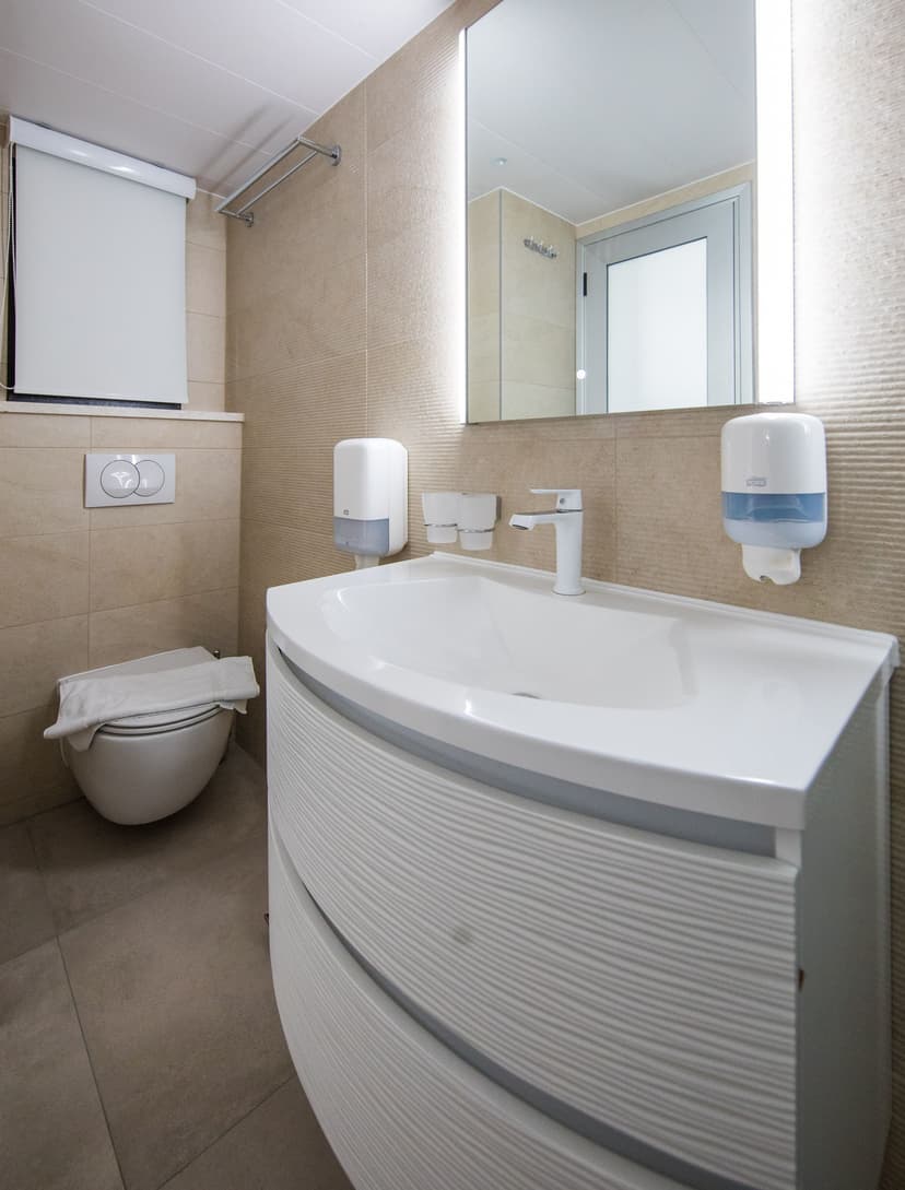 Modern hotel bathroom with white vanity sink, illuminated mirror, and toilet